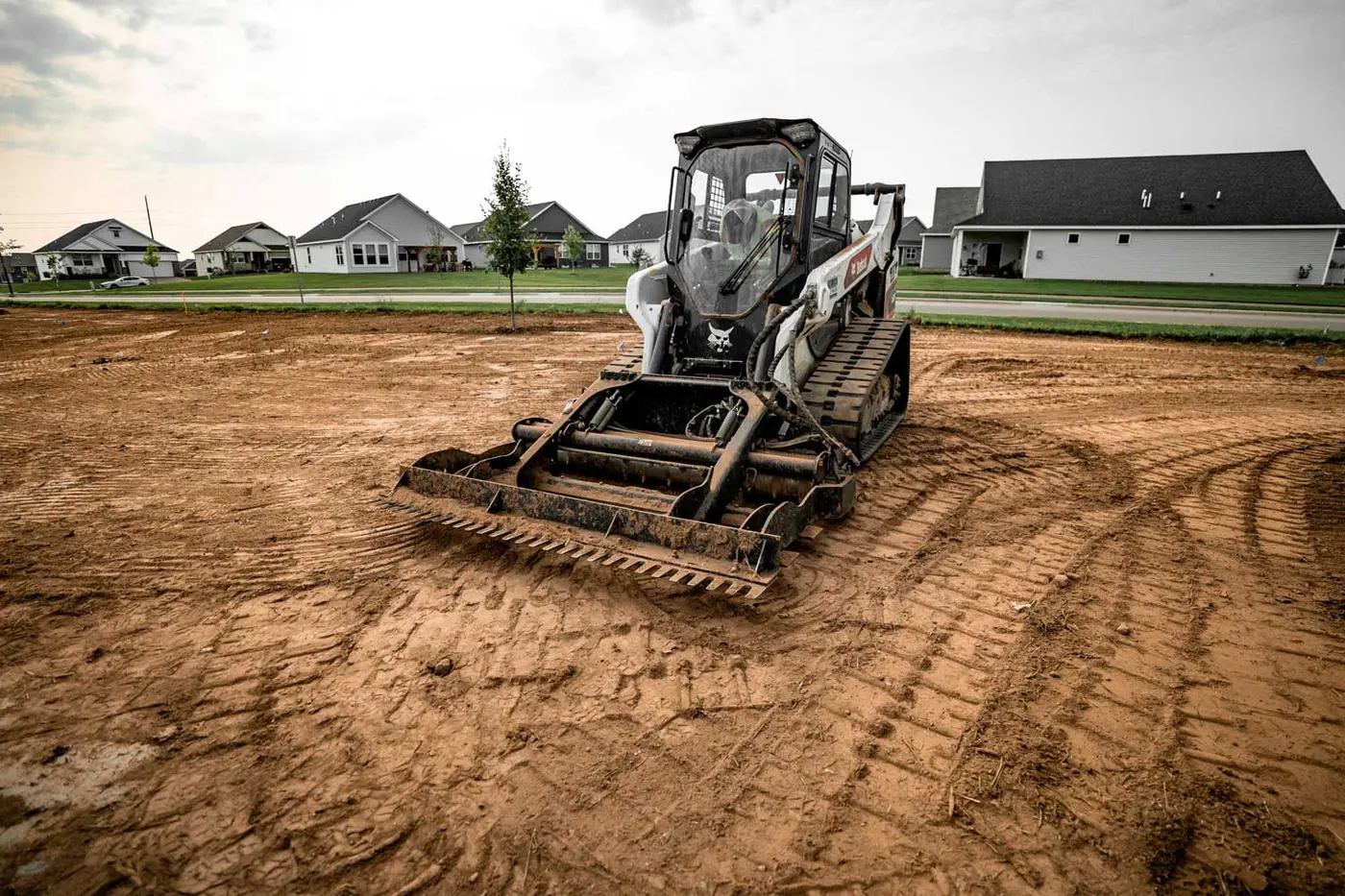Compact track loader leveling and grading a bare residential lot
